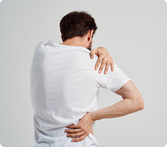 Mladi muškarac u bijeloj majici se rukama drži za bolna leđa